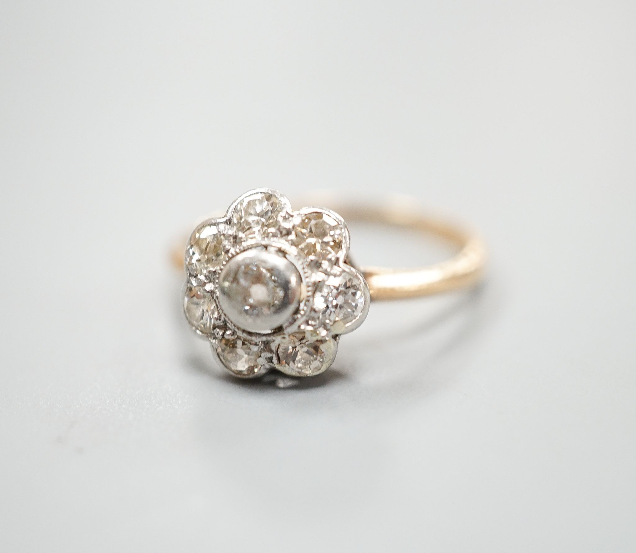 A yellow metal and eight stone diamond set flower head cluster ring, size M, gross weight 2.7 grams.